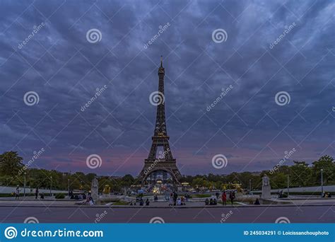 Purple Sky At Evening Over Eiffel Tower With Tourists Denses Clouds And