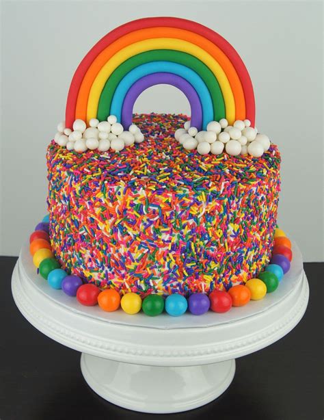 A Rainbow Cake With Sprinkles And Candy On Top