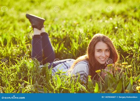 Young Beautiful Redhead Woman Sits On A Green Meadow Looking At Camera