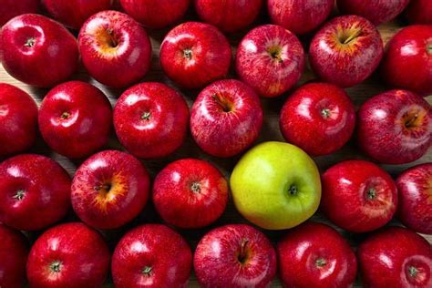 An Apple Surrounded By Many Red Apples On Top Of A Wooden Table With