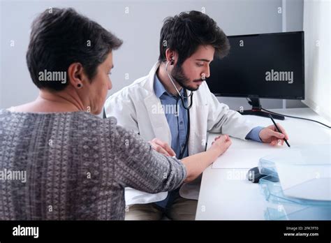 Young Doctor Listening To Mature Woman Patient Heart With A Stethoscope