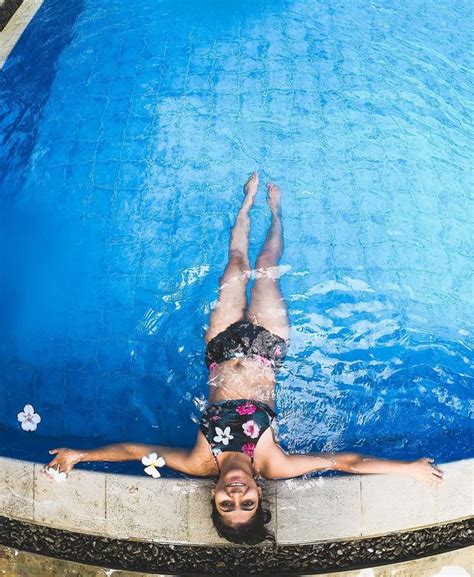 a woman is swimming in a pool with her hands on the side of the pool