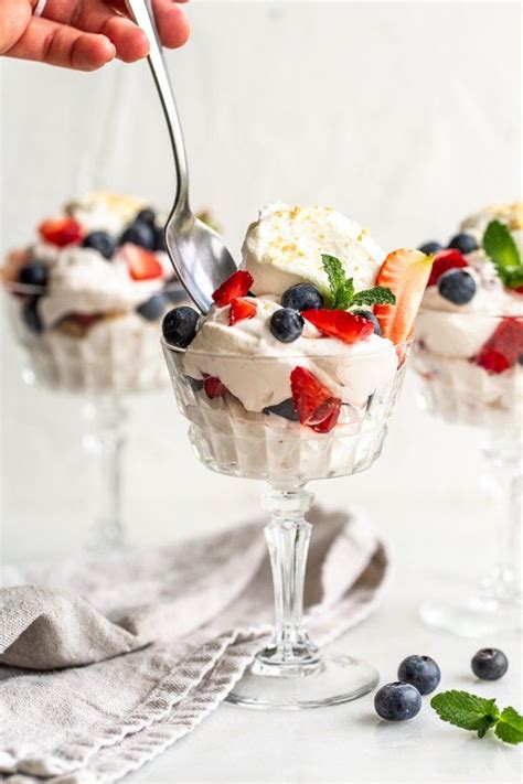 Two Desserts With Berries And Whipped Cream In Small Glass Dishes On A
