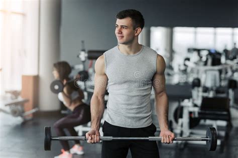 Handsome Muscular Man Working Out With Dumbbells In The Gym Stock Photo