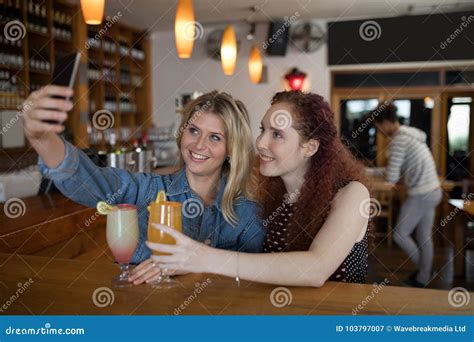 Female Friends Taking Selfie With Mobile Phone While Having Drinks In