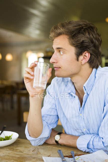 Young Man Sitting And Drinking Water — Looking Away Leisure Activity