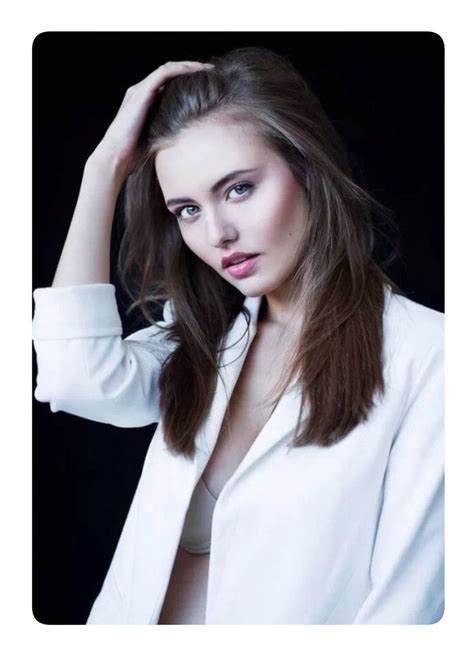 a woman with long hair and white shirt posing for a photo in front of a black background