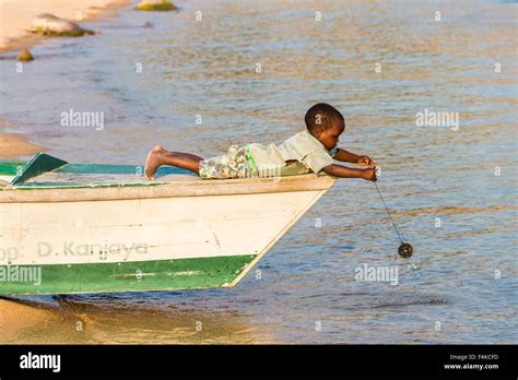 Local Young African Boy Child Laying Down Plays At Fishing From A