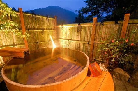 An Outdoor Hot Tub In The Middle Of A Wooden Fenced Area At Night Time