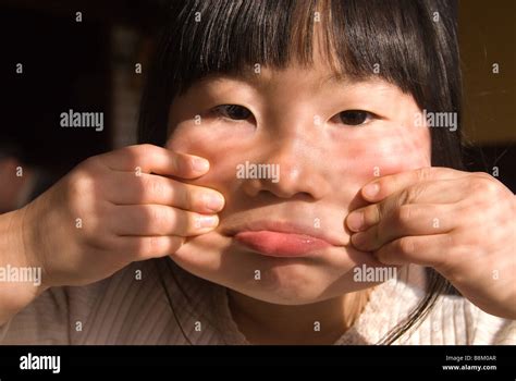 A Young Japanese Girl Makes A Face By Pulling Her Cheeks Out With Her