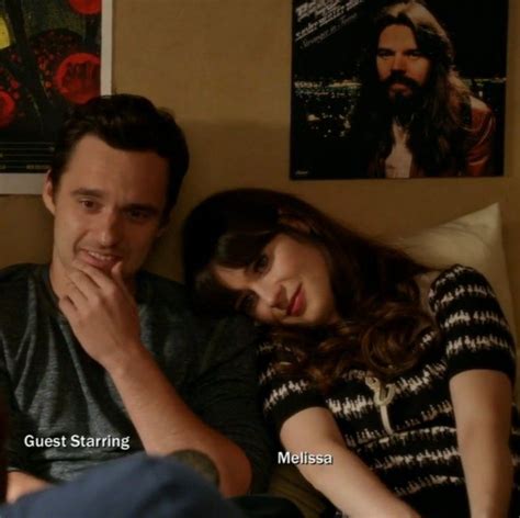 A Man And Woman Sitting Next To Each Other On A Bed In Front Of Posters