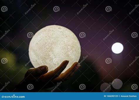 A Picture Of A Hand Holding A Model Of The Moon At Night Stock Image