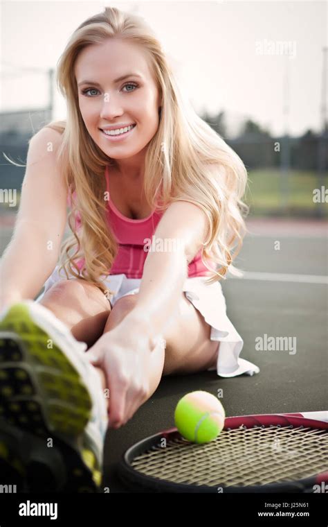 A Beautiful Caucasian Tennis Player Stretching On The Tennis Court