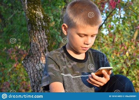 Een Tienerjongen Kijkt Naar Een Buitentelefoon Stock Afbeelding Image Of Hangen Telefoon