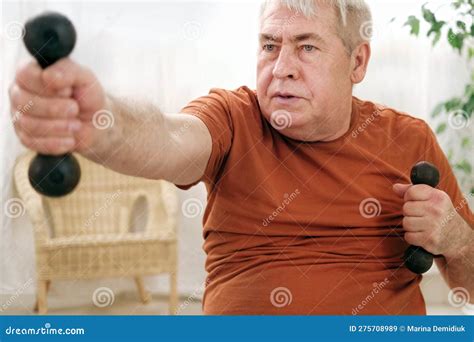 Old Elderly Man In Sportswear Training In Living Room Doing Weight
