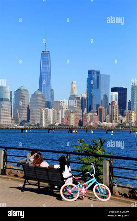 Visitors Relaxing On The Hudson River Waterfront Walkway With Skyline