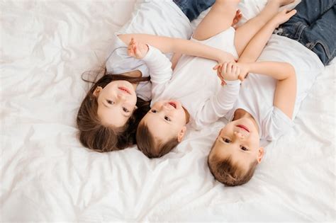 Premium Photo Three Young Children Lie In Bed And Cuddle