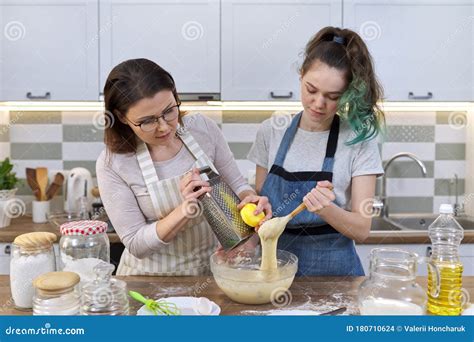 Mother And Teenager Daughter Cook Together At Home In Kitchen Stock
