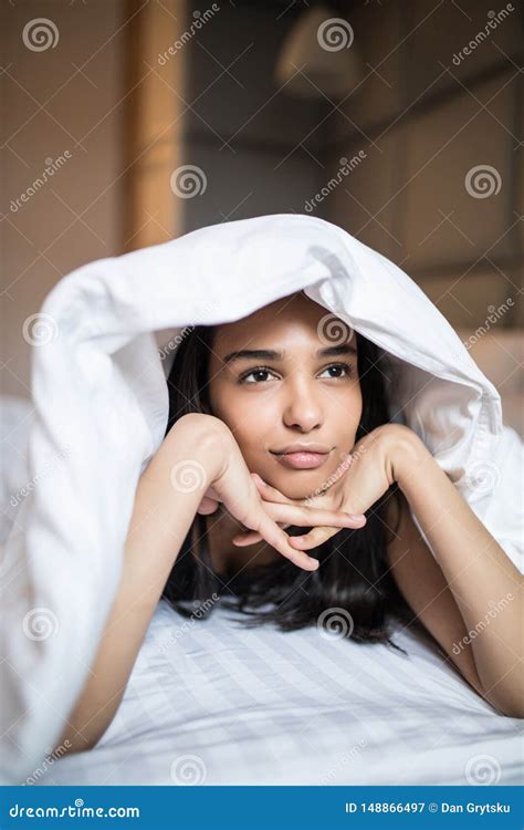 Beautiful Bored Mixed Race Woman Lies In Bed Under Blanket At Home