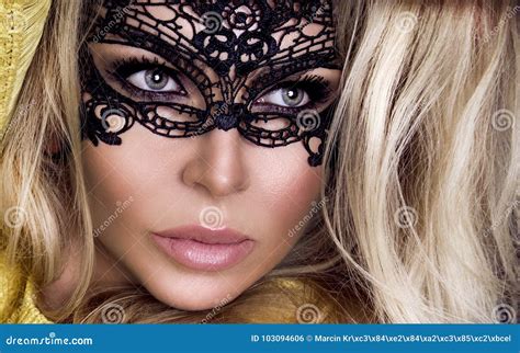 la belle femme blonde sensuelle avec le masque de carnaval sur son visage se tient sur un fond