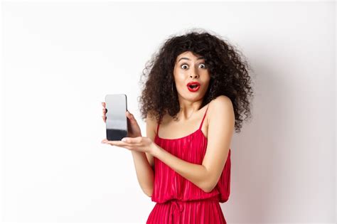 Premium Photo Excited Woman With Curly Hair Makeup And Red Dress Gasping Amazed Showing