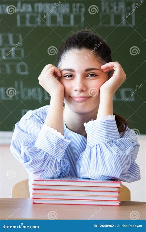 la fille de sourire s assied contre le tableau noir dans la salle de classe image stock image