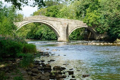 An Old Stone Bridge With Two Arches Crossing A River Stock Photo