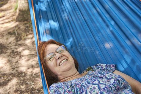 latin mature woman on vacations wearing glasses smiling lying in a blue