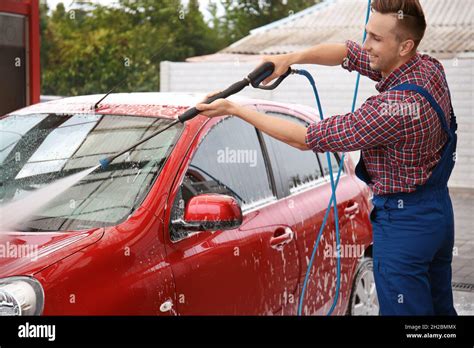 Male Worker Cleaning Vehicle With High Pressure Water Jet At Car Wash