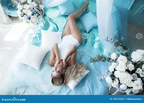 Boudoir Photography Woman Blonde With Long Hair In Lingerie On The Bed Surrounded By Flowers
