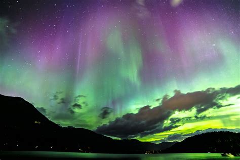 An Aurora Bore Is Seen In The Night Sky Over Water And Mountains With
