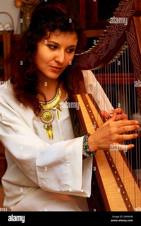 Girl Harpist In White Dress With Jewels Playing Her Instrument Stock
