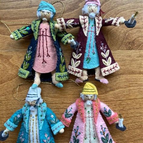 Three Handmade Dolls Hanging From Strings On A Wooden Surface One Is