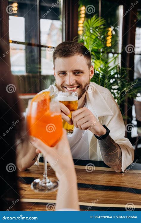 Smiling Attractive Man Is Drinking Beer While Sitting At In Pub With