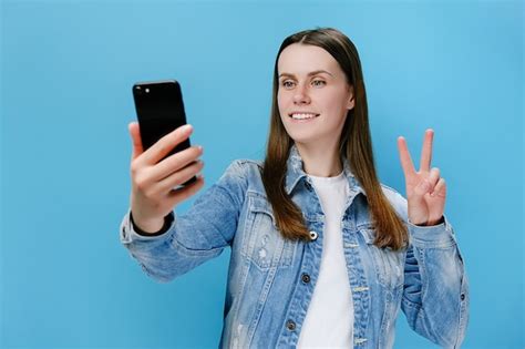 mulher tirando selfie com telefone fazendo gesto de paz foto premium