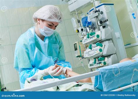 Doctor Examining Newborn Baby In Incubator At Neonatal Resuscitation