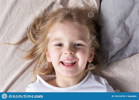 Smiling Little Girl Is Lying On The Bed A Child With