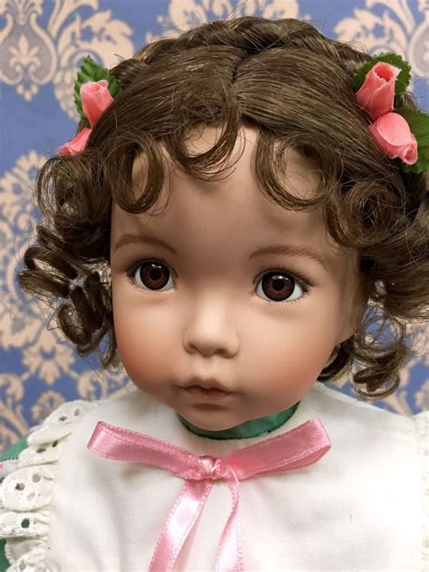 A Close Up Of A Doll Wearing A White Dress And Pink Flowers In Her Hair