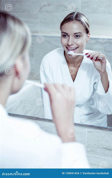 Beautiful Blue Eyed Woman Looking In Mirror While Brushing Her Teeth