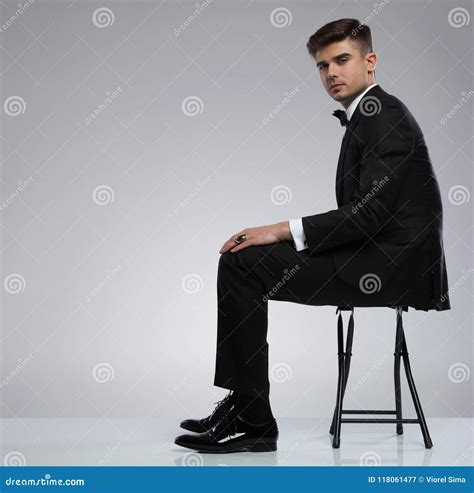 Side View Of Seated Stylish Young Man In Black Tuxedo Stock Image