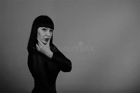 A Beautiful Girl With Dark Hair In A Black Dress Poses On A Dark Background Stock Image Image