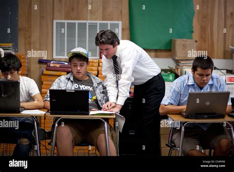 Young Hispanic Male Teacher Helps Hispanic Male Student Using Laptop