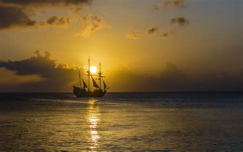 A Ship Sailing In The Ocean At Sunset