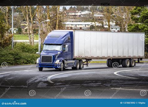 Dark Blue Big Rig Semi Truck With Semi Trailer Driving Under Bridge On