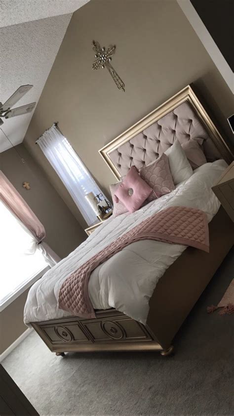 A Bedroom With A Large Bed And Pink Pillows On Its Headboard In Front