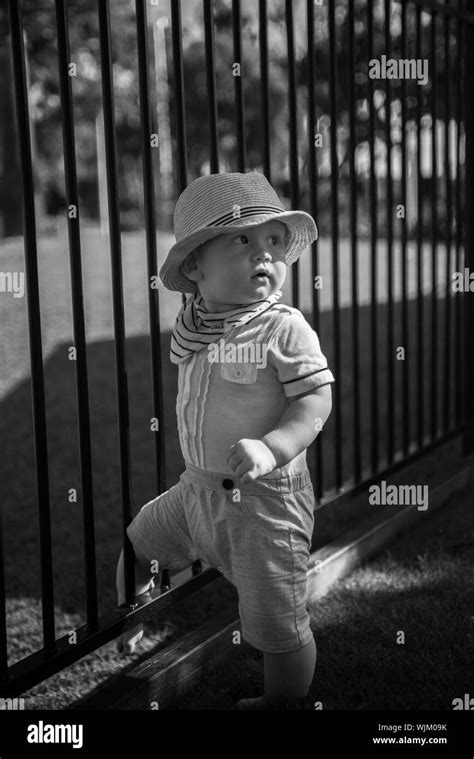 Baby Boy Standing By Fence On Playground Stock Photo Alamy