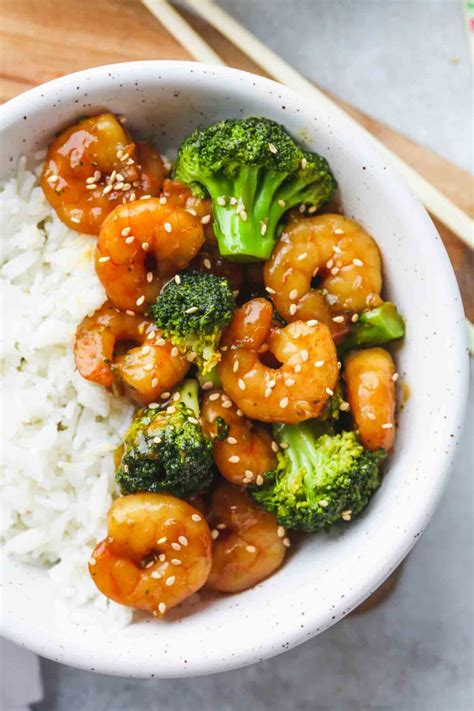Shrimp And Broccoli Garnished With Sesame Seeds Served In A White Bowl