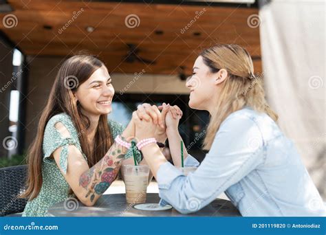 Lesbian Couple Holding Hands While Sitting In A Coffee Shop Stock Photo