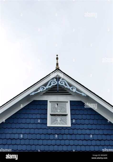 Roof Peak Of House With Ornate Woodwork Blue Shingles And Window