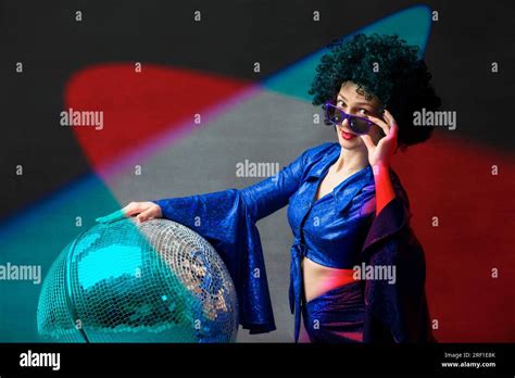 A Woman With A Disco Ball In An Afro Wig In Multi Colored Rays Of Light